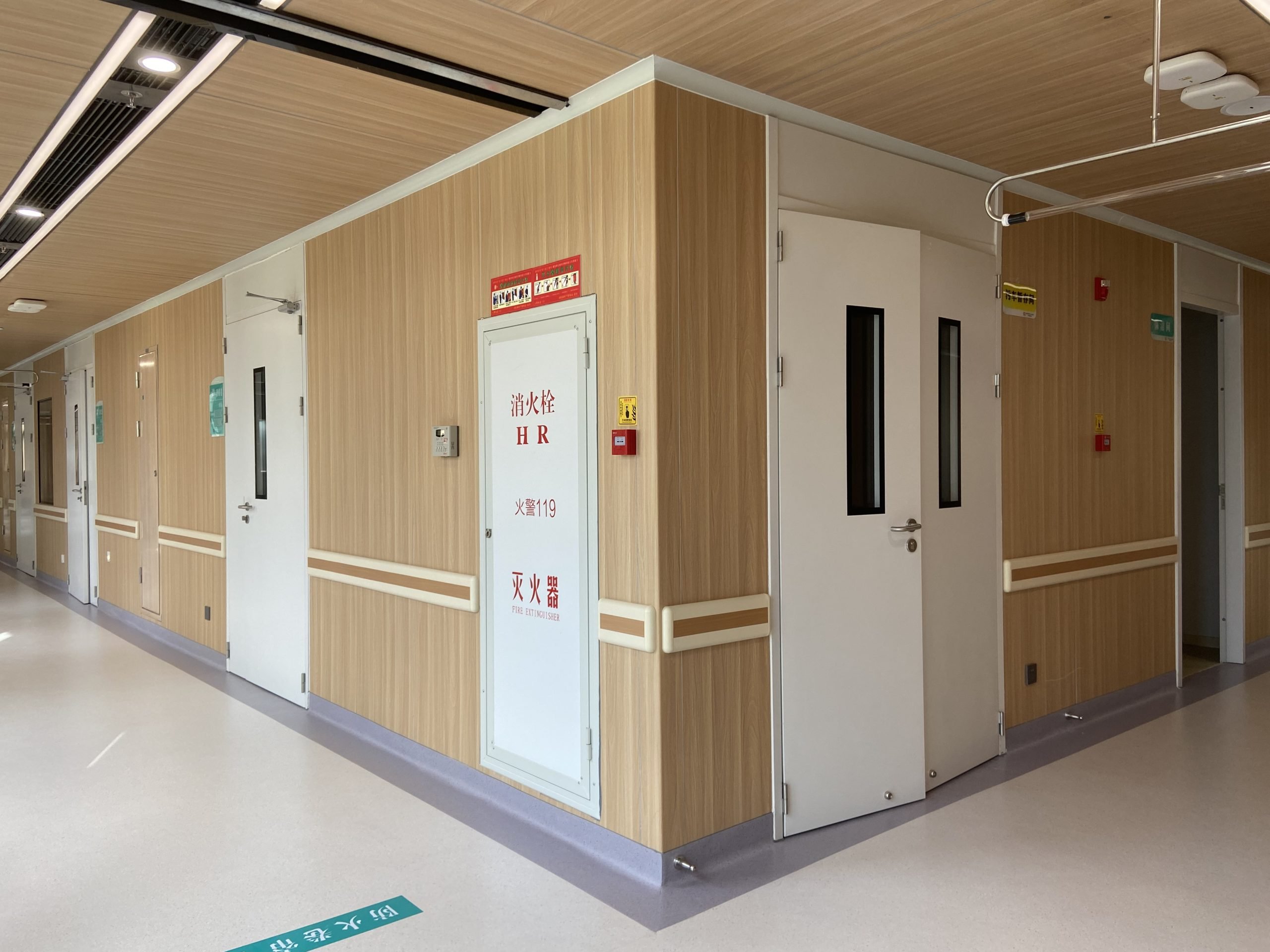 Hospital corridor application scene with wood-grain wall panels, from a product page. This is a general application scene, not a photograph of one named project.